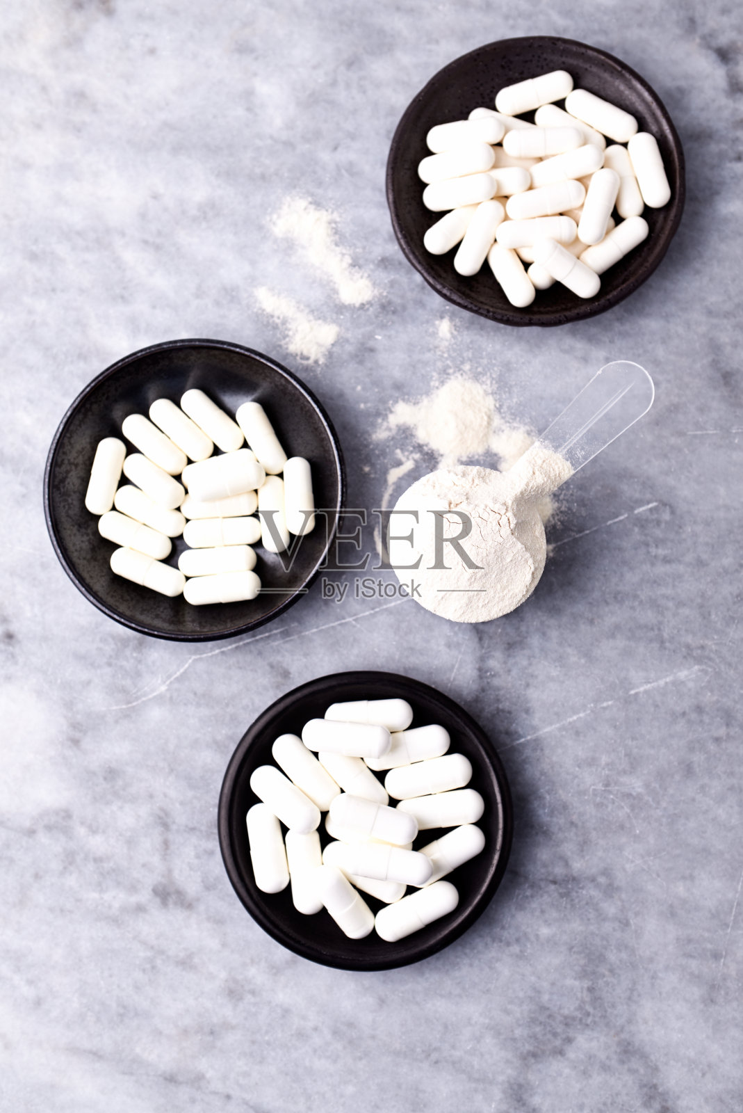 乳清蛋白,水解膠原I型,l -脯氨酸和l -賴氨酸膠囊勺。補充膠原蛋白的生產(chǎn)。明亮的石頭背景。直接上圖。副本的空間。